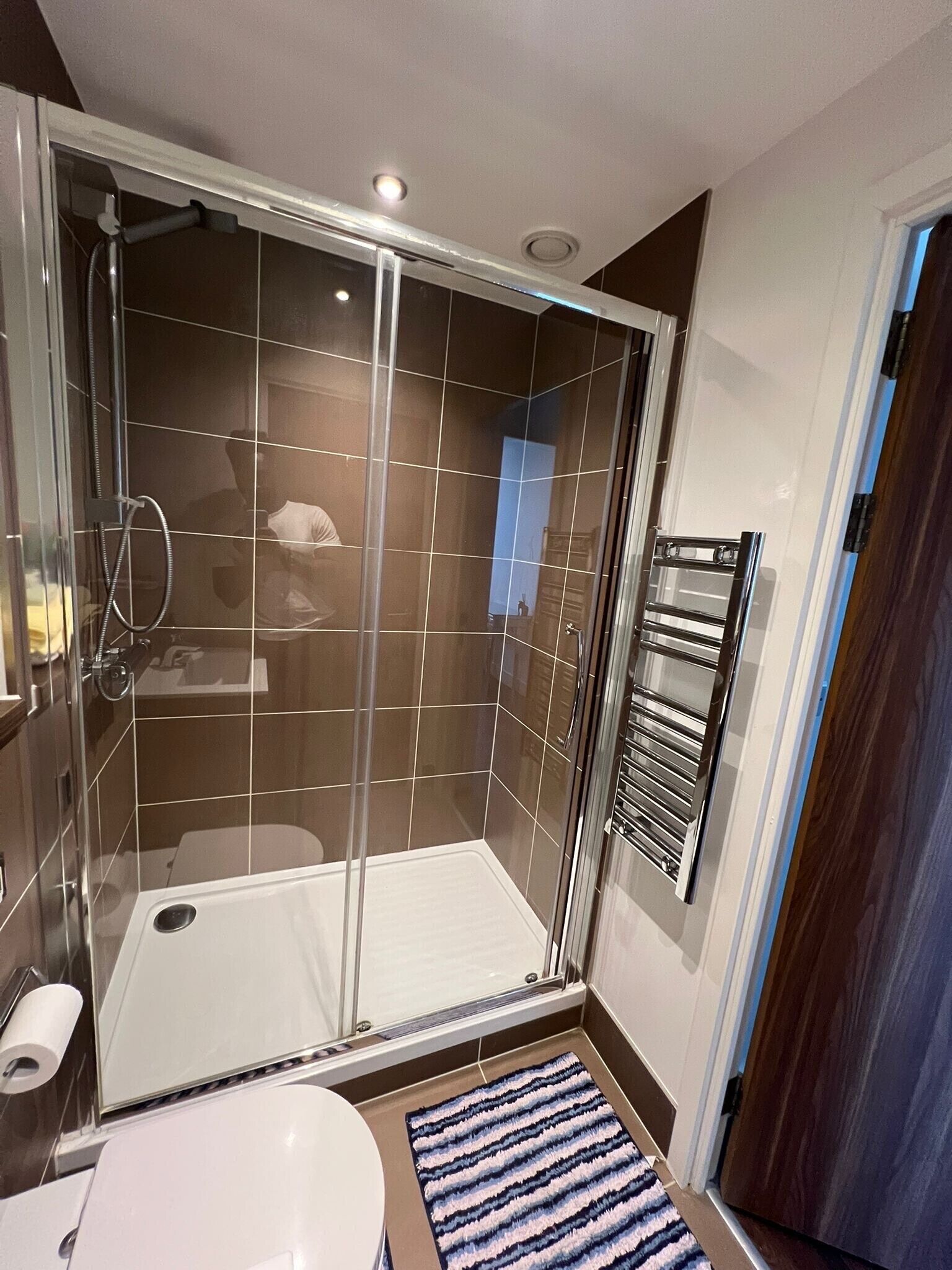A modern bathroom with a glass-enclosed shower, a white toilet, and a towel rack.