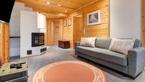 Ein Holzinterieur mit einer Couch, einem Fernseher und einem Kamin.