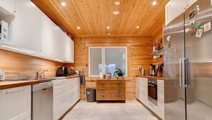 Eine moderne Küche mit Holzwänden, Edelstahlgeräten und einem Fenster.