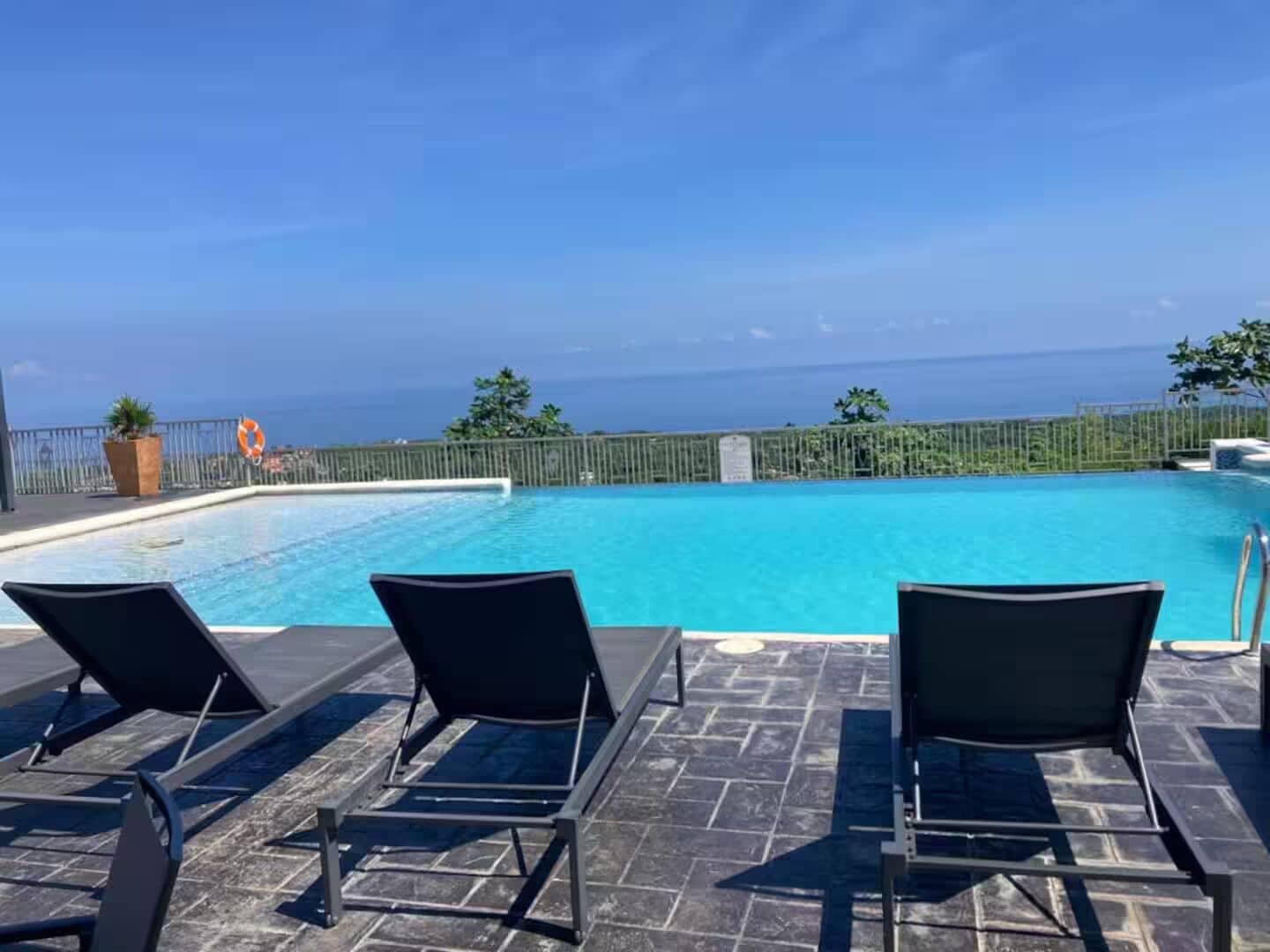A poolside area with lounge chairs and a view of the ocean.