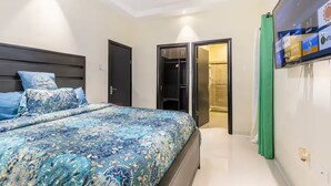 A bedroom with a bed, a wardrobe, and a television mounted on the wall. - Peaceful Hilltop Retreat/Ocho Rios/Community Pool (Ocho Rios)