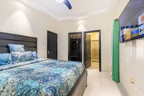 A bedroom with a bed, a wardrobe, and a television mounted on the wall. - Peaceful Hilltop Retreat/Ocho Rios/Community Pool (Ocho Rios)