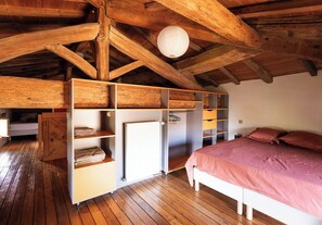 Ein Schlafzimmer mit Holzboden, integrierten Regalen, einem Bett und einer Heizung.