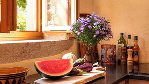 Eine Küche mit einer Holzausziehtheke, einer Schüssel, einer Wassermelone und einer Vase mit Blumen.