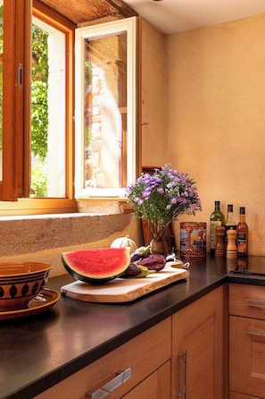 A kitchen with a wooden countertop, a bowl, a watermelon, and a vase with flowers. - Maison Pourpre | Sleeps 10 | Burgundy | Close to the village (Leynes)