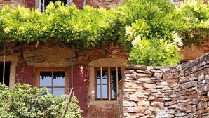 Ein rustikales Steinhaus mit einer hölzernen Treppe, die zu einer Tür führt, und einem kleinen Fenster mit Holzrahmen.