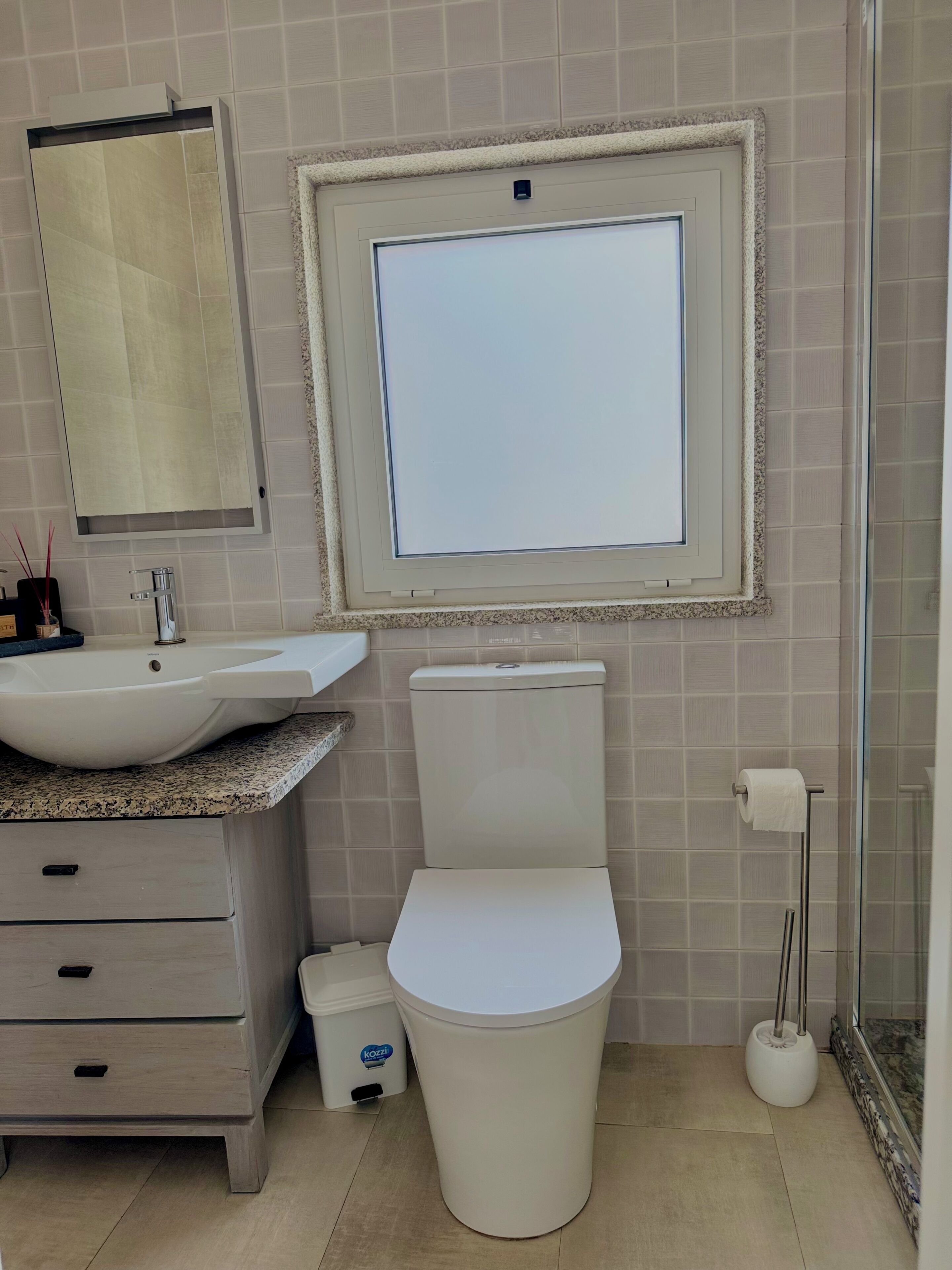 A bathroom with a sink, toilet, and mirror.