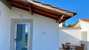 A building with a tiled roof, a door with a glass panel, and a sign labeled 'AL' on the wall. - Casinha dos Carris- AL (Valença)