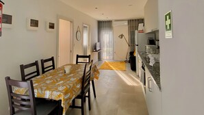 A compact living space with a dining area, kitchenette, and a door leading to an outdoor area. - Casinha dos Carris- AL (Valença)