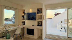 Ein modernes Wohnzimmer mit Kamin, Fernseher und einem Balkon mit Blick auf Gebäude.
