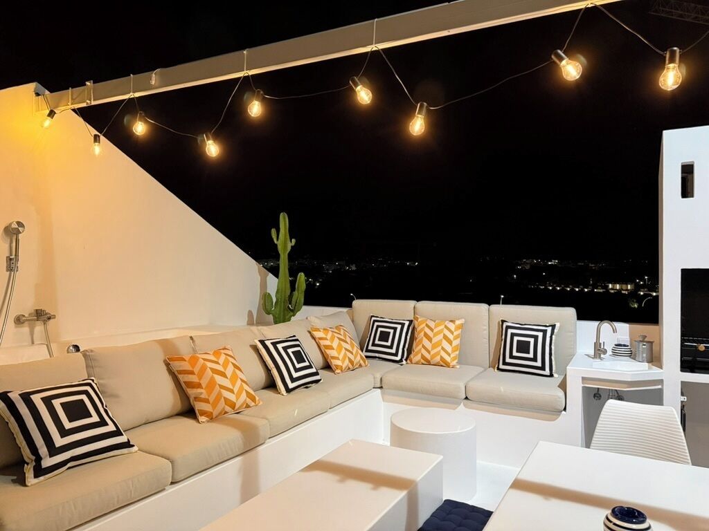 Eine Dachterrasse mit einer Sofagruppe, einem runden Couchtisch und einem kleinen weißen Tisch.