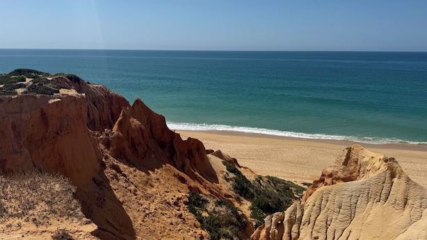 Eine Küstenlandschaft mit Sandstrand und felsigen Klippen.