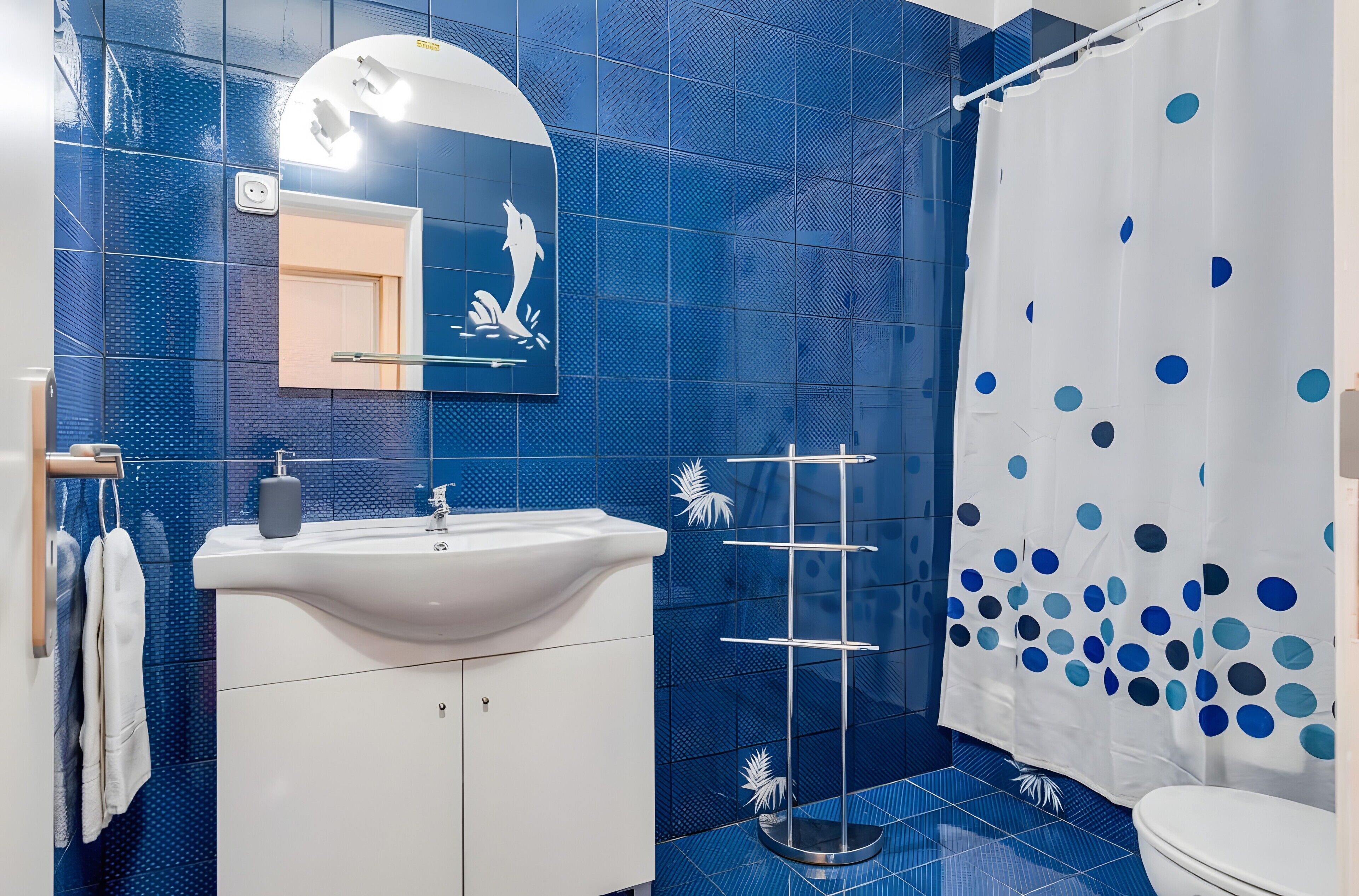 A bathroom with a white sink, mirror, and blue tiled walls.