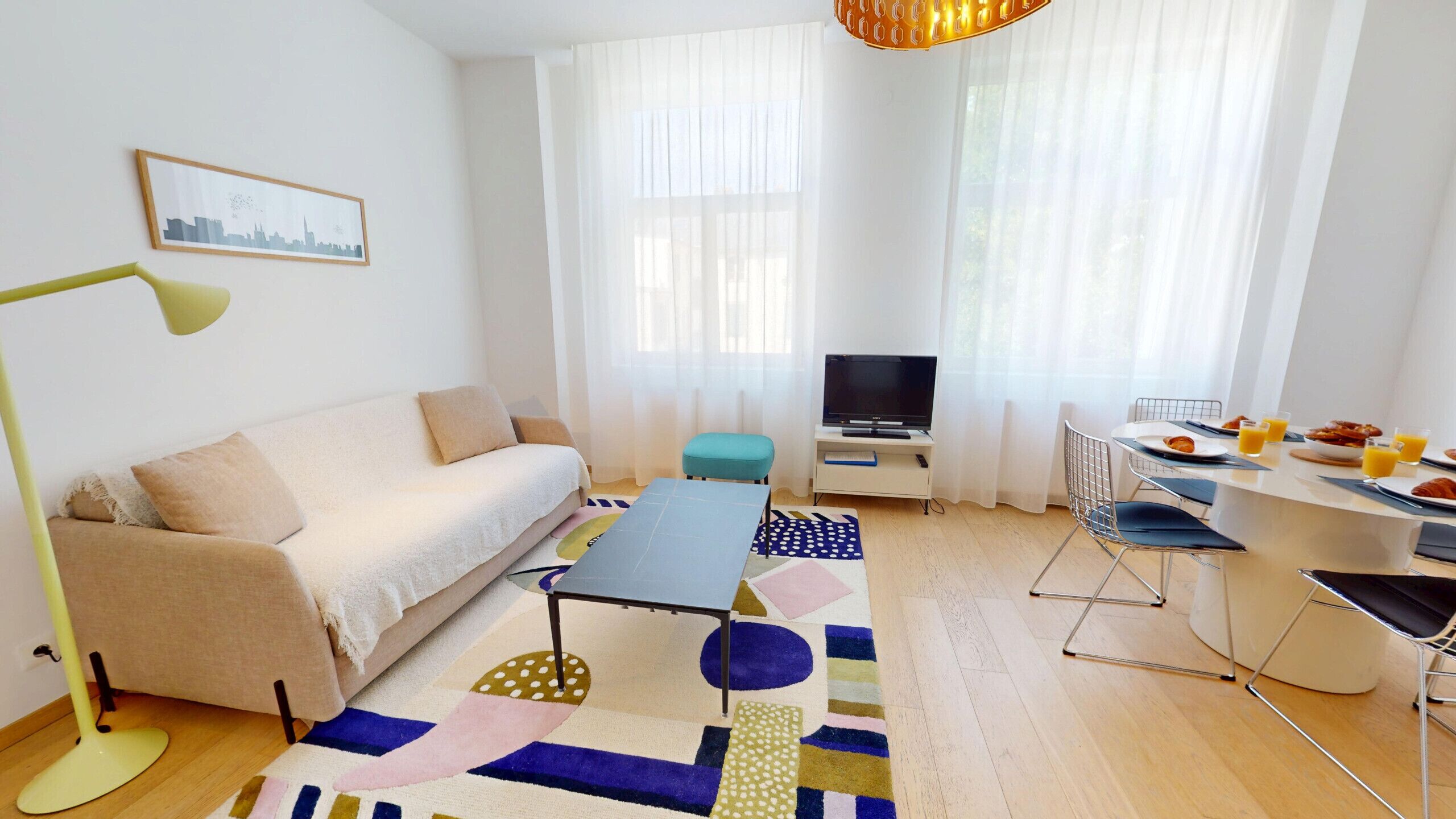 Ein modernes Wohnzimmer mit Sofa, Couchtisch, Fernseher und einer Frühstücksecke.