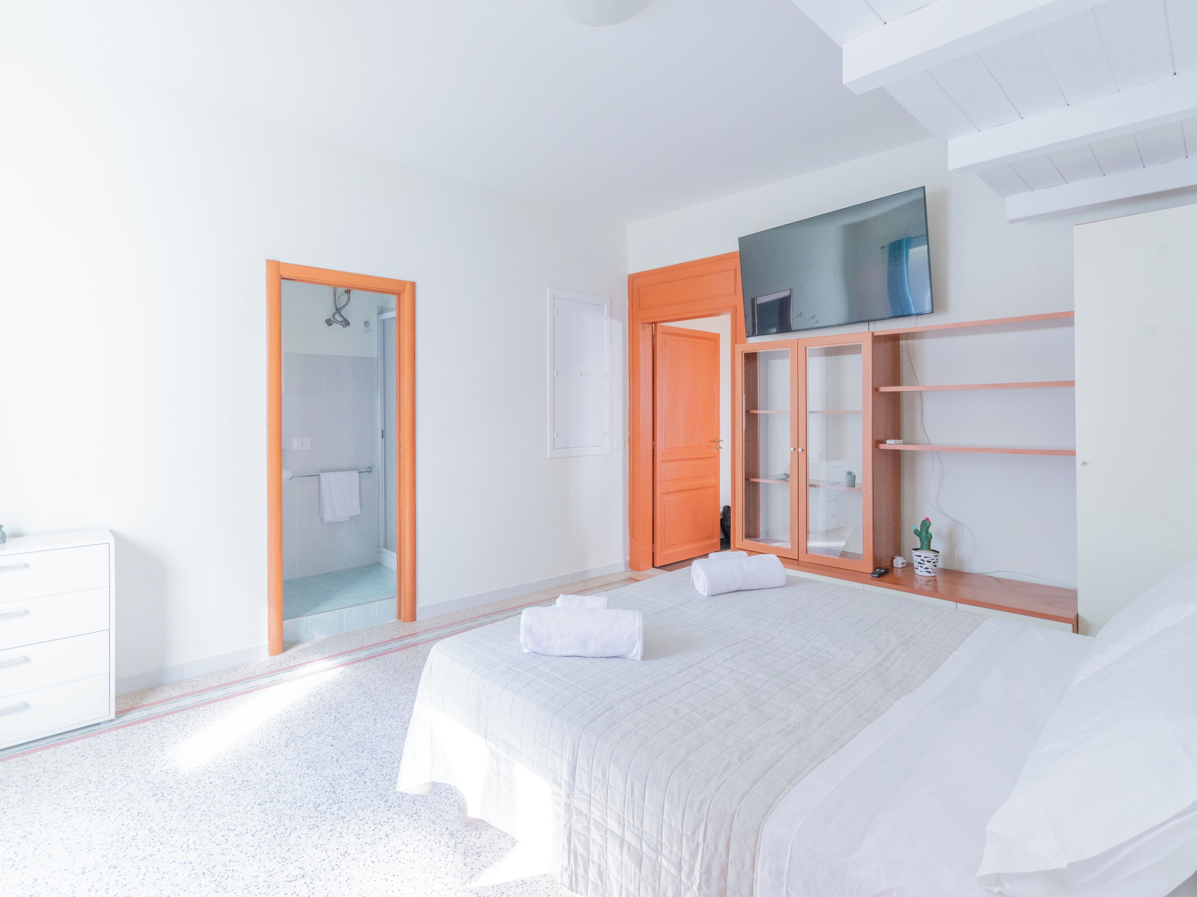 Ein Schlafzimmer mit einem Bett, einem Kleiderschrank, einem Spiegel und einer Tür zu einem Badezimmer.