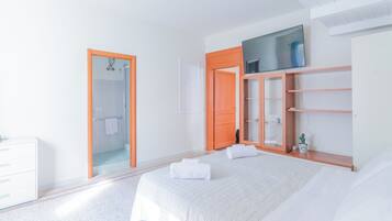 Ein Schlafzimmer mit einem Bett, einem Kleiderschrank, einem Spiegel und einer Tür zu einem Badezimmer.