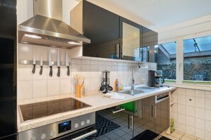 Una cocina moderna con electrodomésticos de acero inoxidable, encimera de granito y ventana con vista a un edificio.