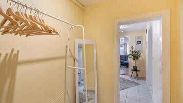 A hallway with a wooden hanger rack, a door leading to another room, and a potted plant.