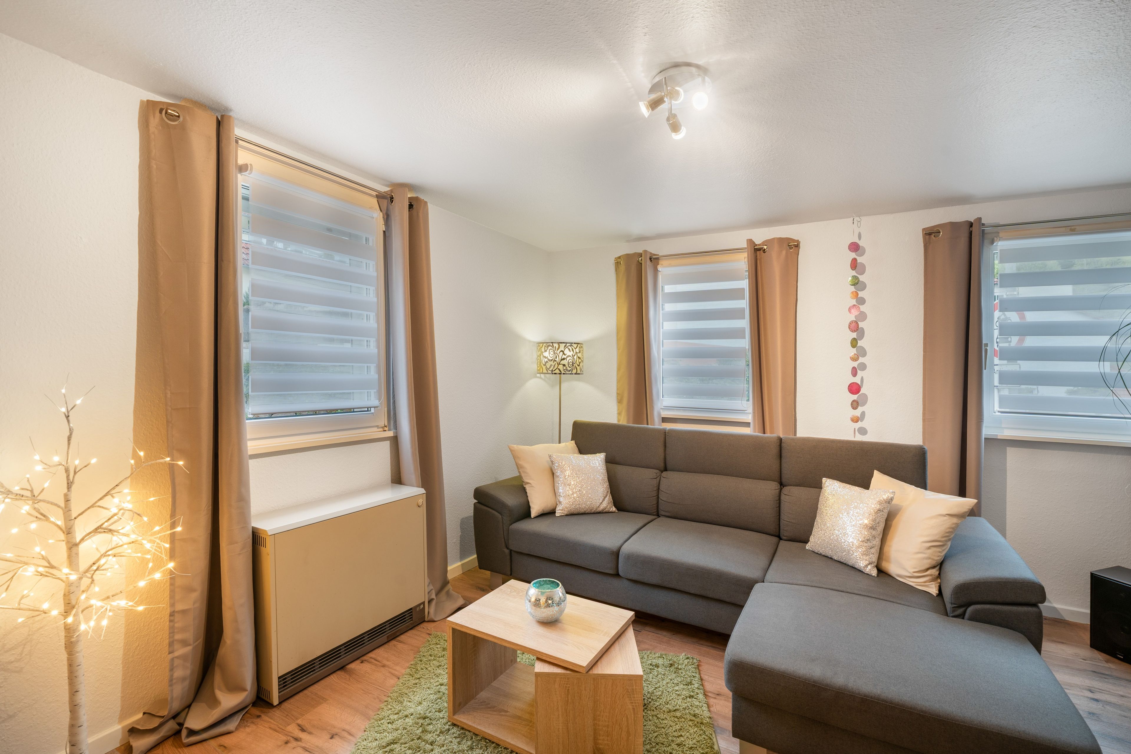 Una sala moderna con un sofá modular, una mesita de madera y un radiador.