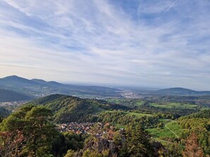 Ein weiter Panoramablick auf eine Stadt, eingebettet in ein Tal, umgeben von Hügeln und einem klaren Himmel.