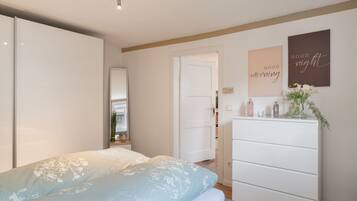 Ein Schlafzimmer mit Bett, Schminktisch und einer Tür zu einem anderen Raum.