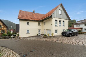 Ein zweistöckiges Haus mit geneigtem Dach, einer Garage und einer gepflasterten Auffahrt.