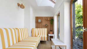 A sunlit room with striped sofas, a small table, and a wooden wall panel.