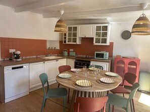 A kitchen with white cabinets, a microwave, a coffee maker, and a dining table set with plates and glasses.