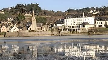 A waterfront view with buildings and a church, reflecting in calm water.