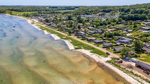 Luchtbeeld van een kustgebied met woonhuizen, een strand en heldere luchten.