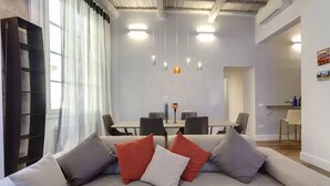 Ein modernes Wohnzimmer mit einer Couch, einem Esstisch und Pendelleuchten.