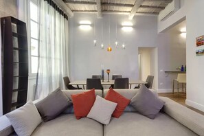 A modern living room with a sofa, a dining table, and pendant lights. - Florence abode with Private Courtyard Near Duomo & Piazza Santa Maria Novella (Firenze)