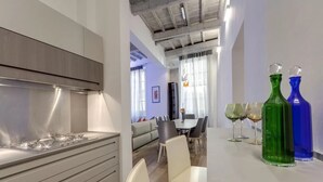 Eine moderne Küche mit Einbauherd, Essbereich mit Stühlen und Tisch sowie dekorative Glasflaschen.