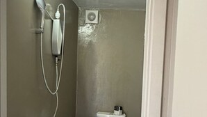 A small bathroom with a toilet, a shower, and a toilet paper holder. - Petite rooftop room for 1person (ATHENS)