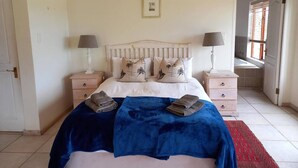 Une chambre à coucher avec un lit, deux tables de chevet, une fenêtre et une porte.