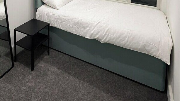 A bedroom with a bed, a window, and a small table.
