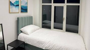 A bedroom with a bed, a window, and a small table.