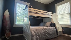 A room with a bunk bed, a ceiling fan, and a surfboard. - The Parlor at Big Red 1903, Charming historic home in historic Dtown Wilmington (Wilmington)