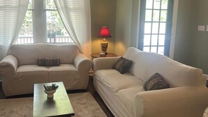 A living room with two sofas, a small table with a plant, a lamp, and a window with curtains. - The Parlor at Big Red 1903, Charming historic home in historic Dtown Wilmington (Wilmington)