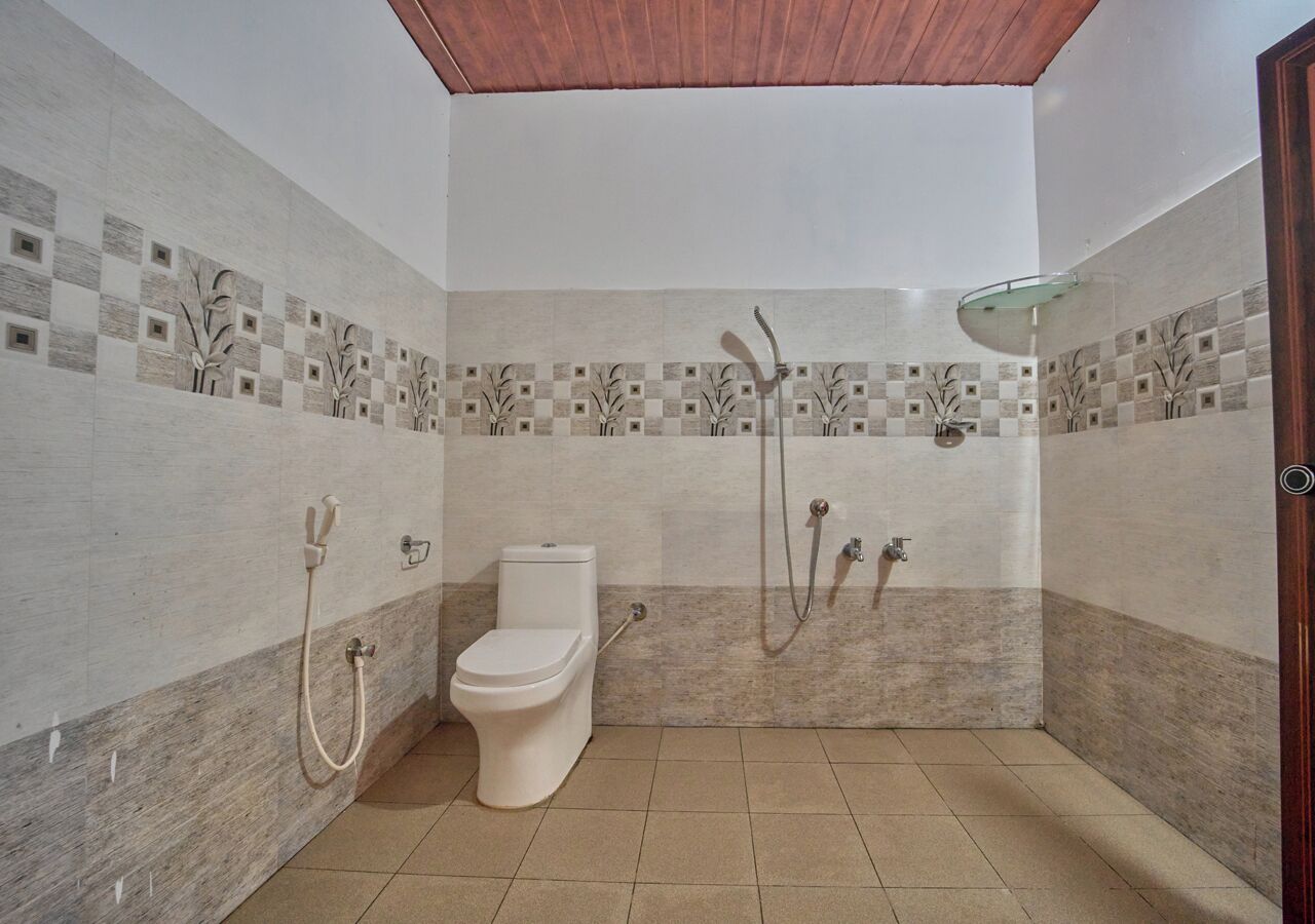 A bathroom with a toilet, shower, and tiled walls.