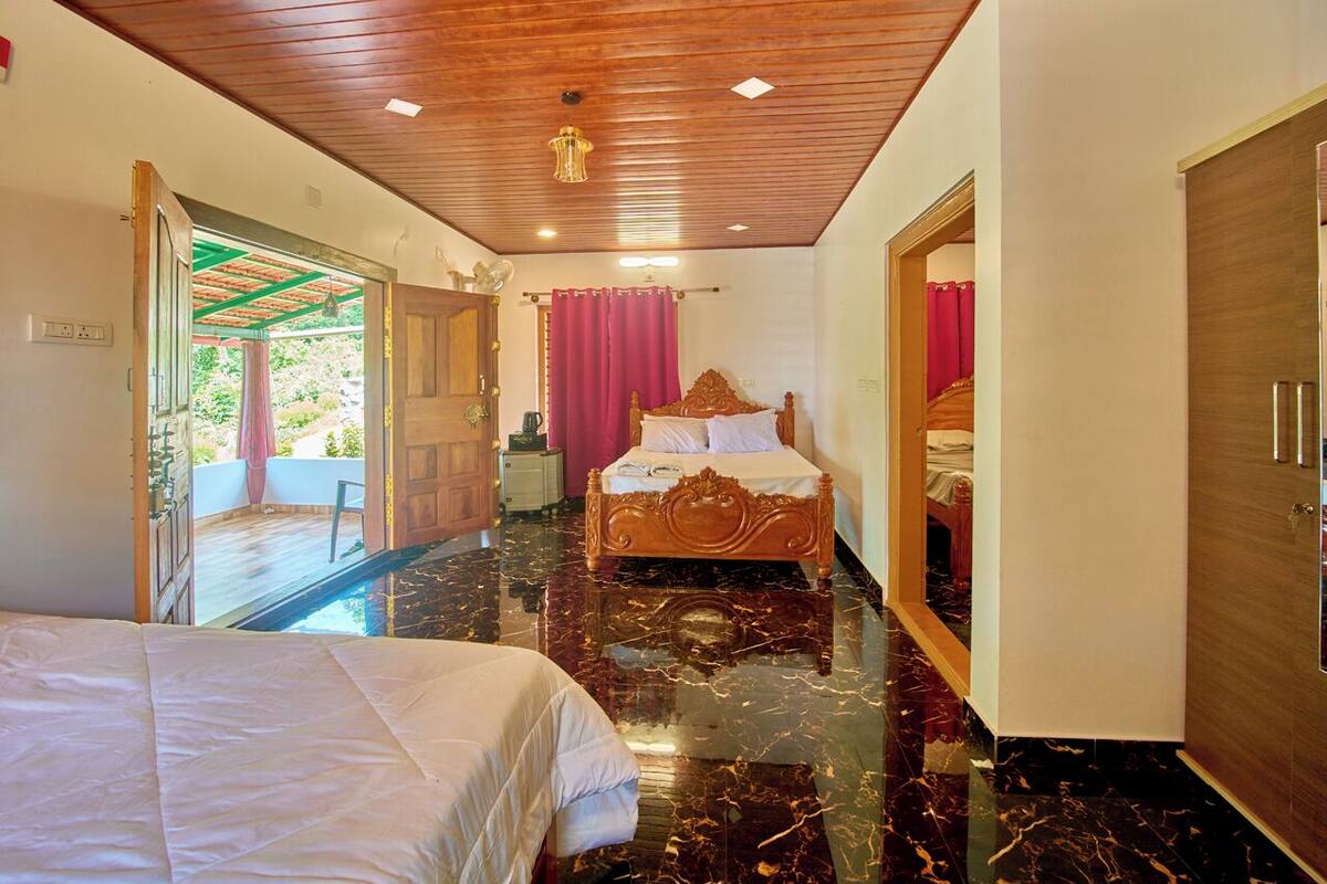 A hotel room with a bed, a wooden ceiling, a marble floor, and a view of a balcony.