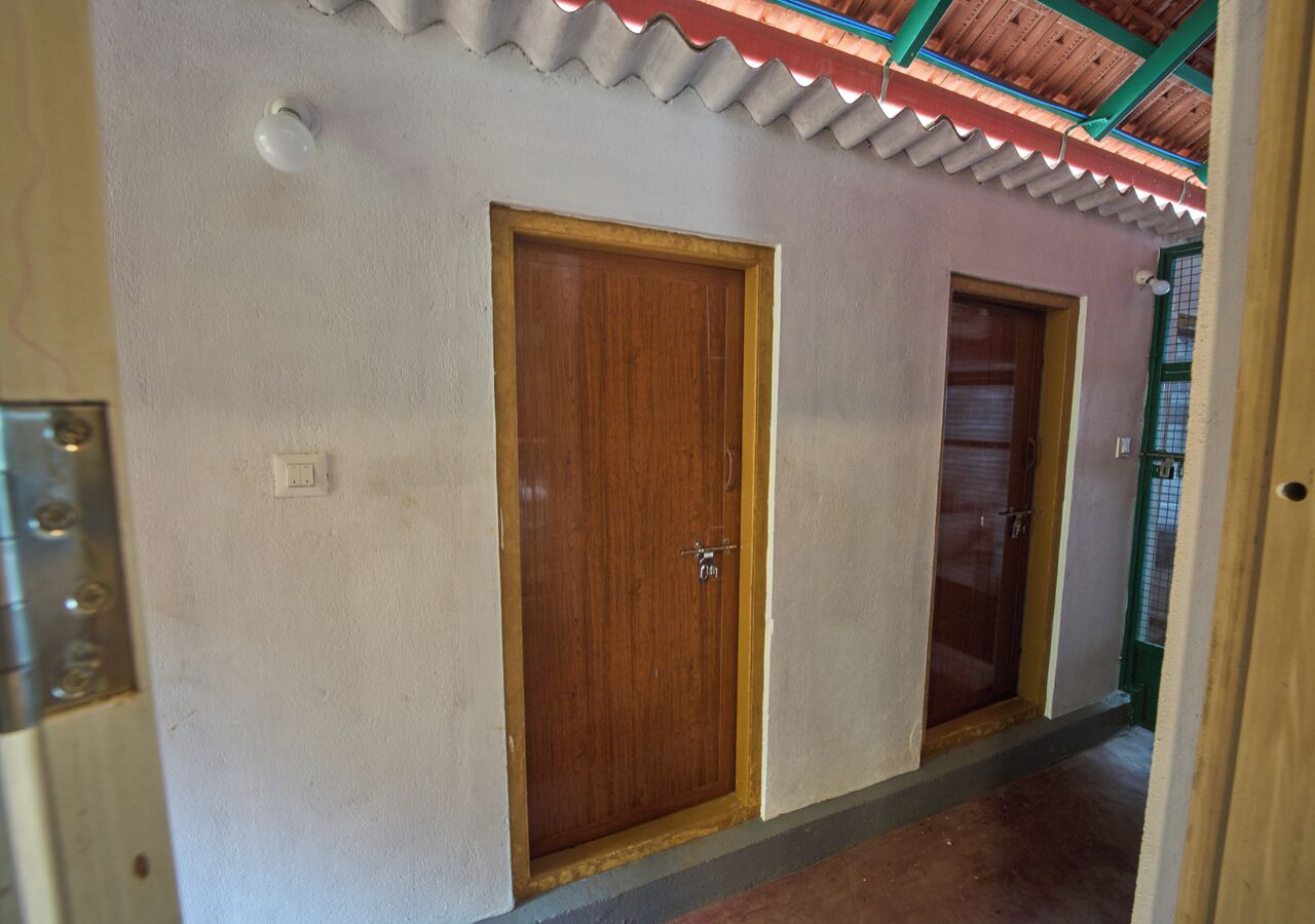 Un pasillo con dos puertas de madera, techo con diseño corrugado y un accesorio metálico en la pared.
