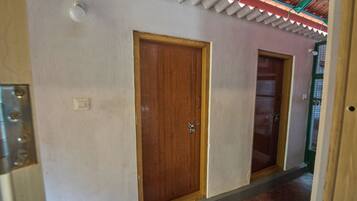 Un pasillo con dos puertas de madera, techo con diseño corrugado y un accesorio metálico en la pared.