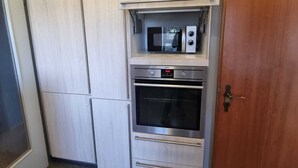 A kitchen with built-in appliances, including a microwave and oven, and a wooden door. - Just like home, D3 OG? (Kreßberg)