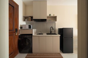 A compact kitchen with a washing machine, microwave, sink, and refrigerator. - Lux Studio in Madison by Maison De Gu (Thành phố Hồ Chí Minh)