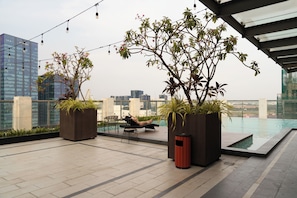 A rooftop terrace with a pool, potted plants, and a person lounging. - Lux Studio in Madison by Maison De Gu (Thành phố Hồ Chí Minh)
