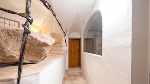 A narrow hallway with a wooden door at the end, a large rock sculpture, and a window on the right wall. - In the heart of Olbia, the gateway to the famous Costa Smeralda, behind the facade of a historic building dating back to 1905, lies a place, renovated and designed by the renowned architect Lesuisse.This luxurious loft, with direct access from the street (Olbia)