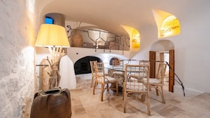 A dining area with a round table and chairs, a fireplace, and wall-mounted lamps. - In the heart of Olbia, the gateway to the famous Costa Smeralda, behind the facade of a historic building dating back to 1905, lies a place, renovated and designed by the renowned architect Lesuisse.This luxurious loft, with direct access from the street (Olbia)