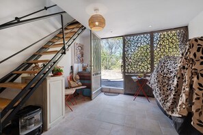 A staircase with a modern design, a large window with a view of greenery, and a bed with a leaf-patterned cover. - Apartment 'Suzette' with Mountain View, Wi-Fi, and Air Conditioning (La Colle-sur-Loup)