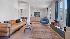 Ein modernes Wohnzimmer mit einem Ledersofa, einem blauen Sessel, einem Couchtisch und einer Kommode mit Dekorationselementen.